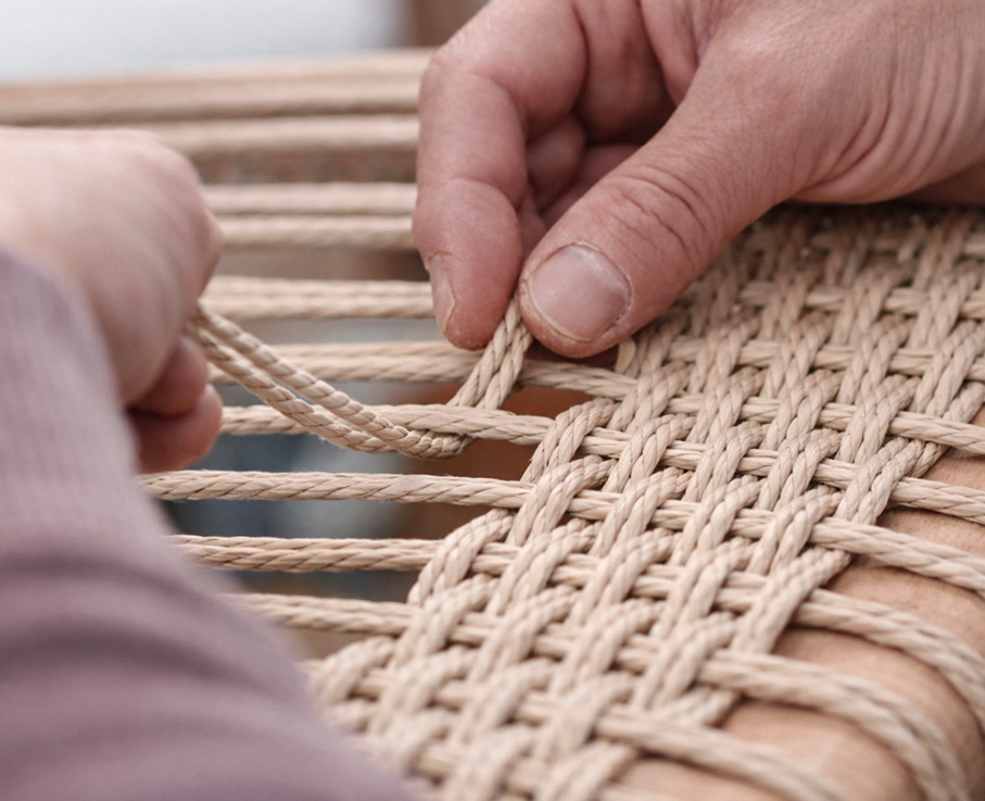Flechter arbeitet mit dänischer Papierschnur und flechtet eine Stuhlsitzfläche in Handarbeit