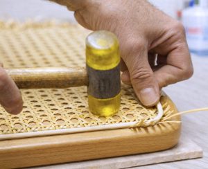 Splintpeddig wird mit Hammer in die Nut eines Thonet Freischwinger eingesetzt – Fixierung von Wiener Geflecht