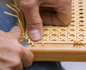 Überschüssiges Wiener Geflecht wird nach dem Einpressen des Splintpeddigs bei einem Thonet Freischwinger sauber abgeschnitten